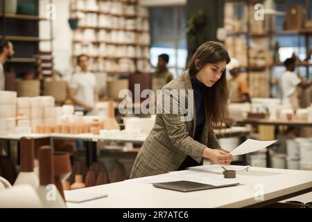 Ceramics studio manager signing paperwork at a table Stock Photo