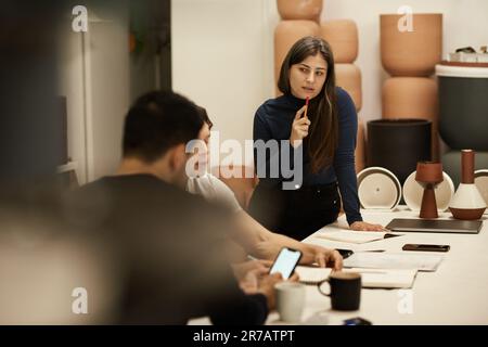 Ceramics designers talking together at a studio table Stock Photo