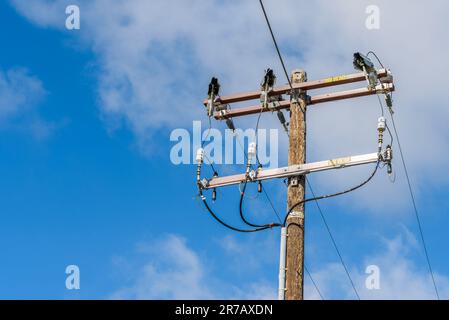 Close up of a wooden post supporting high voltage cables on a sunny autumn day Stock Photo