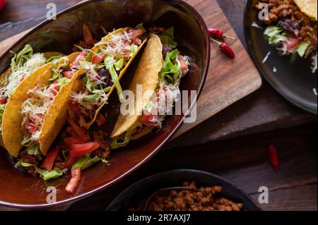 Tacos with ground beef, cheese, kidney beans, lettuce and tomatoes on wooden table Stock Photo