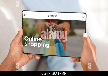 Man shopping online via digital tablet, choosing new clothes at store, sitting at home, enjoying mobile app, closeup Stock Photo