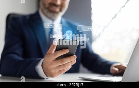 Cropped businessman sitting at workplace, using chat bot on phone Stock Photo