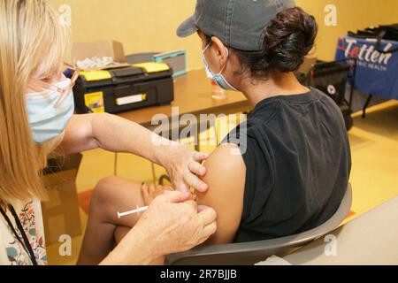 A female patient is receiving a vaccine injection from a nurse in a clinic Stock Photo