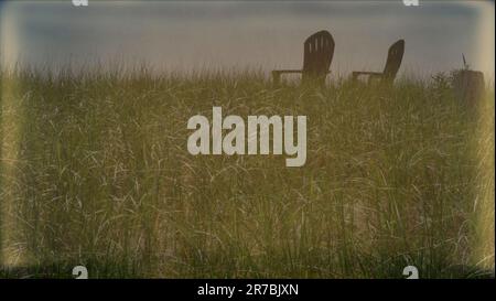 Empty lawn chairs on the grassy hill under blue sky in summer Stock Photo