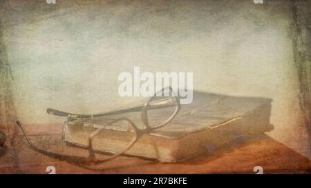 Background graphic resource template of reading glasses siting on top of weathered and tattered book on the table Stock Photo