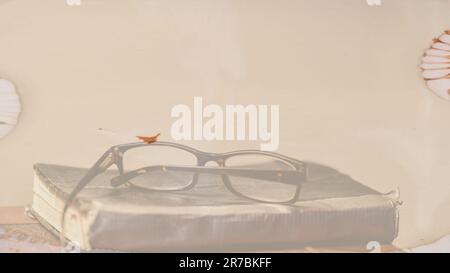 Background graphic resource template of reading glasses siting on top of weathered and tattered book on the table Stock Photo