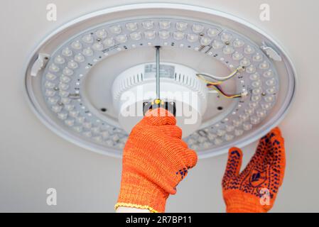 An electrician installs a chandelier on the ceiling.  Stock Photo
