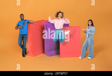 Cheerful multicultural millennials posing next to huge shopping bags, collage Stock Photo
