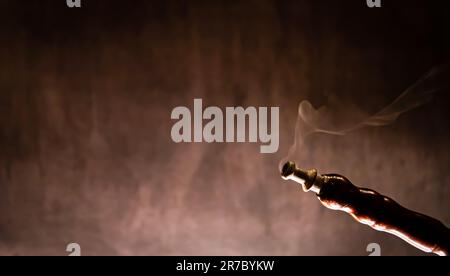 hookah with a glass flask and a metal bowl shisha with colored smoke on the table on a black background with a copy space Stock Photo