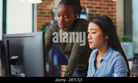 Multiethnic team of IT developers working on computers to create artistic machinery software, using 3d interface. Engineering experts analyzing infographics to create project in agency studio. Stock Photo