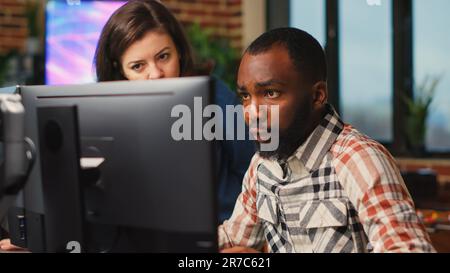 Diverse team of employees working on software development with manufacturing interface, infographics. IT engineers brainstorming ideas to develop production with artificial intelligence. Stock Photo