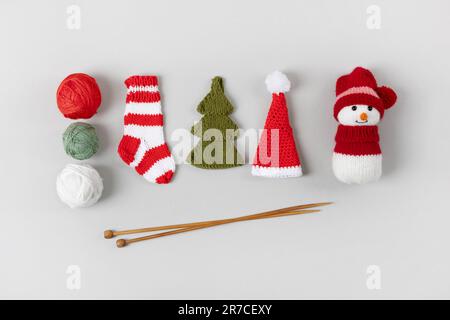 Knitting gifts for winter holidays. Knitted Christmas striped sock, snowman, Santa Claus hat and green Christmas tree with balls of thread and knittin Stock Photo