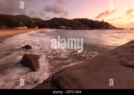 a sunset over waves in bay at Alma Bay on Magnetic Island Stock Photo