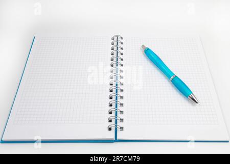 An open and blue spiral-bound notebook, with a blue pen resting on it, with copy space Stock Photo