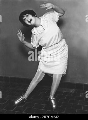 Chicago, Illinois:  September 28, 1927 A young woman tries out a dance step with a pair of industrial steel overshoes at National Safety Congress. Stock Photo