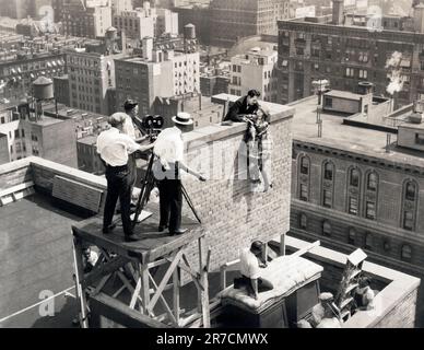 New York, New York:  1925   A stunt scene atop the Algonquin Hotel with star Allene Ray hanging on and Walter Miller doing the life saving in the Pathe Exchange silent film, 'Play Ball'. Stock Photo