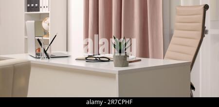 Cozy receptionist workspace with laptop on desk in office Stock Photo