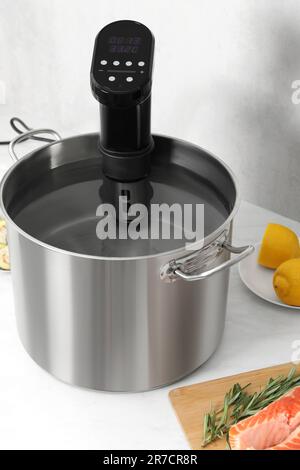 Sous vide cooker in pot on white table. Thermal immersion circulator Stock Photo
