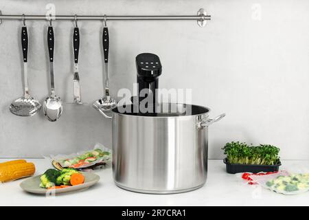 Sous vide cooker in pot and ingredients on white table. Thermal immersion circulator Stock Photo