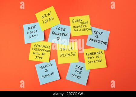 Paper notes with life-affirming phrases on orange background Stock Photo