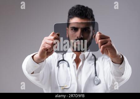 Image ready for your graphics. A blurred doctor in the background holding an in-focus transparent digital tablet in mid-air. Technology and future. CO Stock Photo