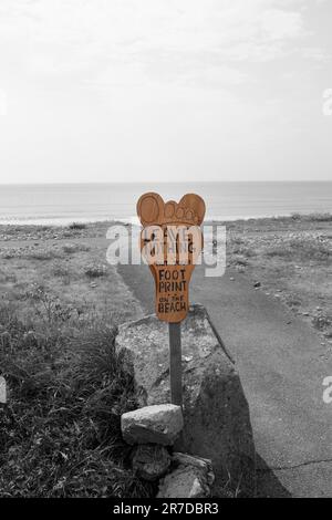 Wooden no littering sign in the shape of a foot. It reads Leave nothing but your footprint on the beach. Ecological clean beach environment concept Stock Photo