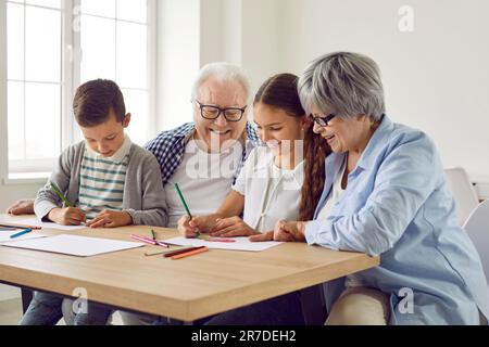 Loving mature grandparents helping grandchildren with school homework at home Stock Photo