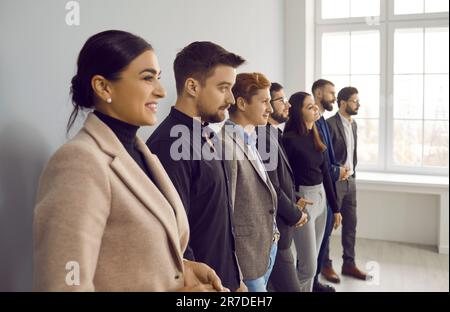 Side view of happy, young, beautiful business lady standing next to her smiling colleagues. Stock Photo