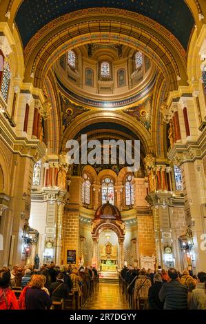 Oviedo, Spain - February 12, 2023: A church congregation stand in the pews facing the altar and clergy. The building's architectural features, interio Stock Photo