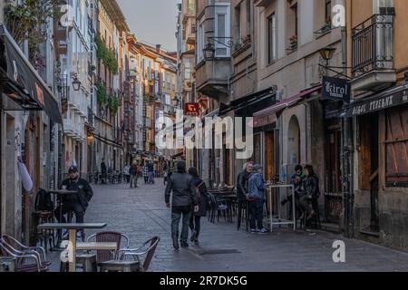 Vitoria-Gasteiz, Spain - 26 March 2023: People enjoying drinks in a colorful street with flowers on balconies Stock Photo