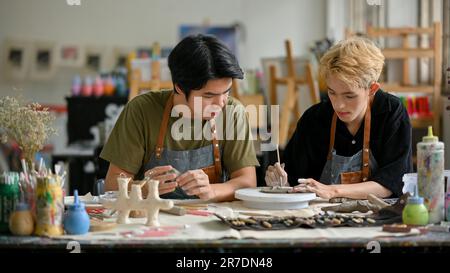 Two young Asian men join in a handicraft workshop and enjoy making clay ornaments or earthenware in the workshop together. Stock Photo