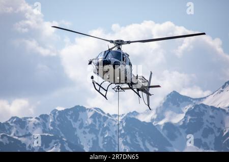 Close-up of a helicopter in the swiss mountains with rope for transport attached Stock Photo