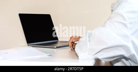Laptop with blank screen on the desk in front of business person, computer networking, online meeting, video call, web conference, corporate virtual c Stock Photo