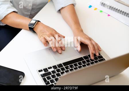 High angle view of hands of business person and laptop on the desk in the office. Stock Photo