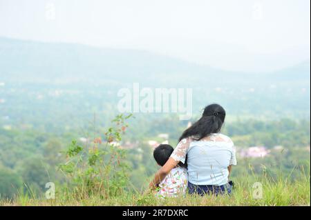 Two young adults sitting on the ground with their hands resting behind them in a relaxed manner Stock Photo