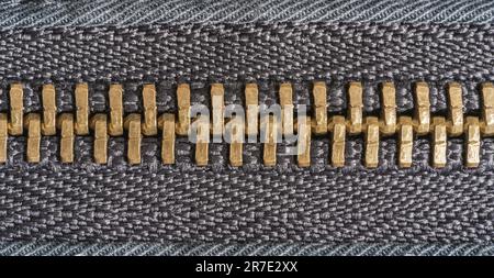 Macro close up of a gold zipper tightly closed together on a black jacket Stock Photo