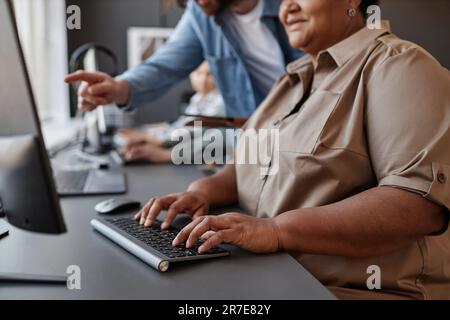 Closeup of black senior woman using computer with teacher in computer class, copy space Stock Photo