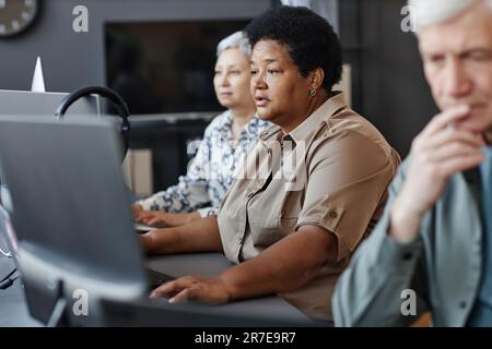 Side view portrait of mature black woman using computer in programming class for seniors Stock Photo