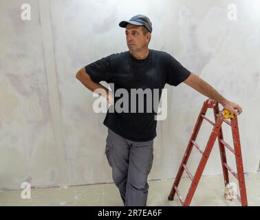 Male builder, master office, plasterer with a tool in working clothes Stock Photo