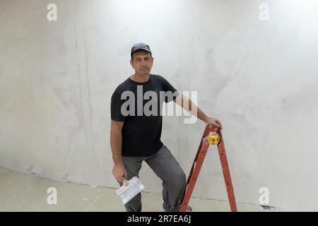 Male builder, master office, plasterer with a tool in working clothes Stock Photo
