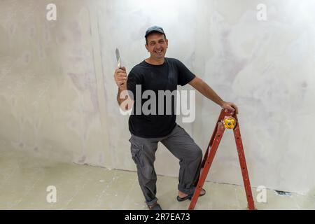 Male builder, master office, plasterer with a tool in working clothes Stock Photo
