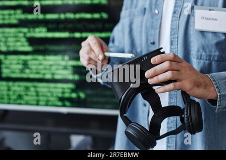 Closeup of man holding VR headset against screen with code lines while developing virtual reality software, copy space Stock Photo