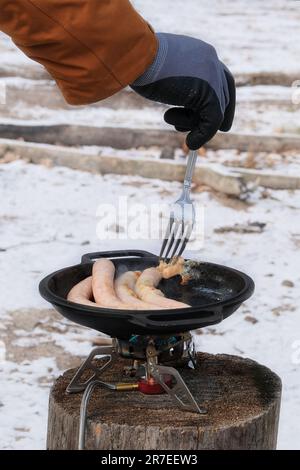 Sausages in bowler in the forest in winter. Travelers foods in outdoor activities. Camping food making. Stock Photo