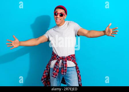 Photo of funny excited man wear grey t-shirt dark glasses open arms ready hug you isolated blue color background Stock Photo