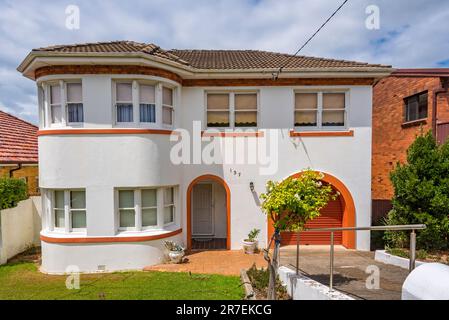 A two storey interwar style home in Dover Heights, Sydney painted white with unusually bright orange highlights and matching orange garage roller door Stock Photo