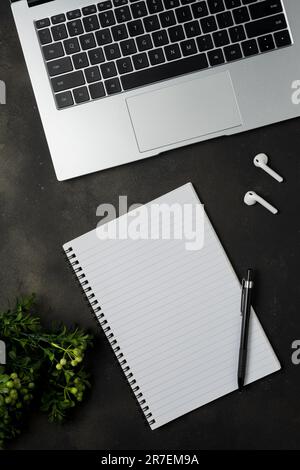 Modern desk with laptop, earphones and blank notebook. Top view with copy space. Stock Photo