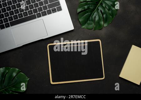 Workspace with blank clip board and laptop on black background. Flat lay, top view office table desk. Stock Photo