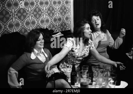 Byker and St Peters Working Men's Club, Newcastle upon Tyne, Tyne and Wear, northern England circa 1973. A group of women friends enjoy a singsong, and a pint or two, it’s Saturday night out - to have fun.   1970S UK HOMER SYKES Stock Photo
