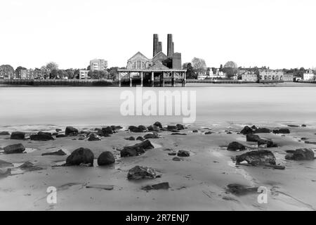 Greenwich Power Station, London. Across the Thames at low tide. Slow shutter speed to blur the water. Black and white photograph Stock Photo