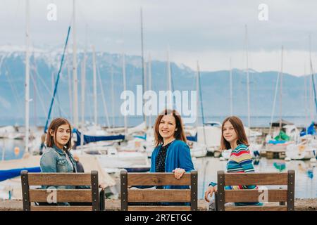 Outdoor portrait of happy mother and two young teenage girls resting by the lake. Image taken in Lausanne, Switzerland Stock Photo